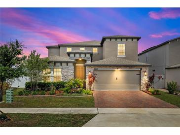 Beautiful two-story home featuring a brick driveway, attached two-car garage, and manicured landscaping at 5637 Beggs Road, St Cloud, FL 34771