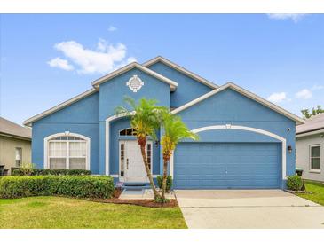Charming single-story home boasts a light blue exterior and a well-manicured lawn with tropical landscaping at 1730 Ribbon Falls Pkwy, Orlando, FL 32824