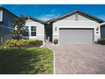 Charming single-story home with a manicured lawn, brick driveway, and two-car garage at 2168 Marsh Sedge Ln, Winter Park, FL 32792