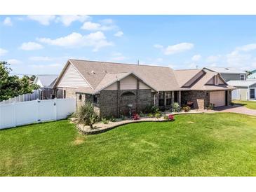 Charming single-story brick home featuring a manicured lawn, water feature, and a white picket fence at 30 Capistrano Dr, Ormond Beach, FL 32176