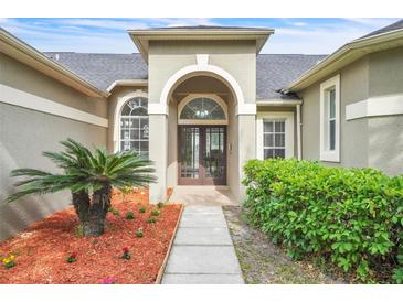 Inviting front entrance with double doors, arched transom window, and lush landscaping at 339 Hammock Dunes Pl, Orlando, FL 32828