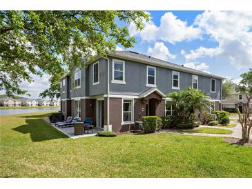 A two-story townhome has a patio with seating overlooking a large lawn and a serene lake at 6672 S Goldenrod Rd # 132B, Orlando, FL 32822