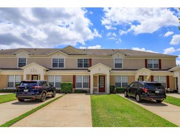 A charming townhome exterior boasting well-maintained landscaping, and a welcoming facade under a bright, cloudy sky at 8110 Princess Palm Ln, Kissimmee, FL 34747