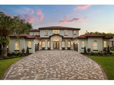 Stunning two-story home boasting a red tile roof, brick driveway, and meticulous landscaping at 11019 Kentmere Ct, Windermere, FL 34786