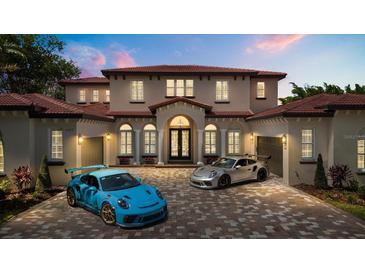Stunning two-story home with red tile roof, arched windows, grand entrance, and two sports cars in the brick driveway at 11019 Kentmere Ct, Windermere, FL 34786