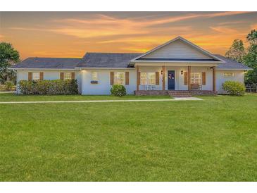 Charming home with shuttered windows, front porch with wooden columns and a large lawn at sunset at 1271 Thoroughbred Trl, Sanford, FL 32771