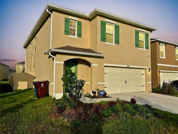 Two-story home featuring tan siding, green shutters, and a well-maintained front yard at 1800 Post Oak Dr, Davenport, FL 33837