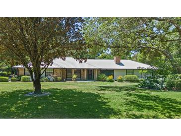 Charming single story home with a metal roof, brick accents, and mature landscaping in a park-like setting at 203 E Greentree Ln, Lake Mary, FL 32746