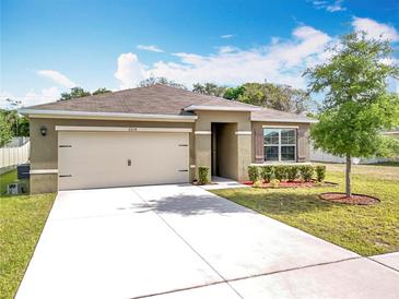 Charming single-story home featuring a well-manicured lawn, fresh landscaping, and an attached two-car garage at 2636 Grand Central Ave, Tavares, FL 32778