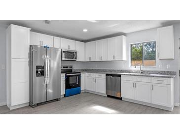 Modern kitchen features stainless steel appliances, granite counters, and white cabinets at 2763 E Waco Dr, Deltona, FL 32738