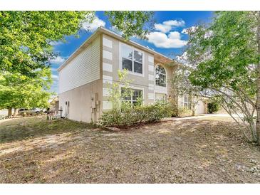 Two-story home with a mix of stucco and siding and trimmed windows, nestled amongst mature trees and a green front lawn at 2995 White Magnolia Loop, Clermont, FL 34711