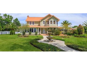 Charming two-story home with lush landscaping, mature trees, and a decorative fountain in the front yard at 36408 E Eldorado Lake Dr, Eustis, FL 32736