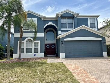Charming two-story blue home featuring a two-car garage, well-maintained lawn, and mature palm tree at 405 Bella Vida Blvd, Orlando, FL 32828