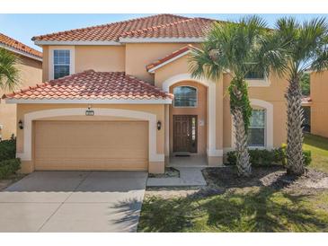 Charming two-story home featuring a red tile roof, arched doorway, and well-maintained landscaping with mature palm trees at 411 Cabello Dr, Davenport, FL 33837