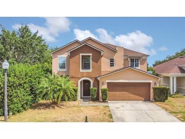 Charming two-story home showcasing neutral tones, arched entryway and a well-manicured lawn at 5056 Gandross Ln, Mount Dora, FL 32757