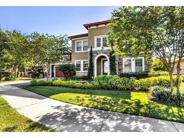 Charming two-story home features stone accents, arched entryway, and lush, mature landscaping at 7225 Sangalla Dr, Windermere, FL 34786