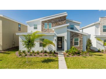 Inviting modern two-story home featuring a textured stone facade and well-manicured lawn at 9332 Sommerset Hills Dr, Davenport, FL 33896