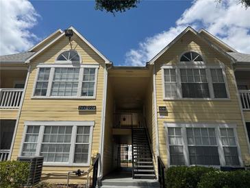 Two-story condo with bright yellow siding, white trim and decorative windows under a partly cloudy blue sky at 1081 S Hiawassee Rd # 726, Orlando, FL 32835