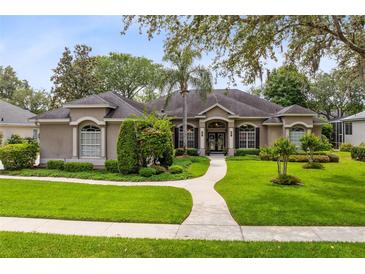 Stunning single-story home featuring a manicured lawn, mature trees, and a welcoming walkway leading to the front entrance at 1525 Eagle Nest Cir, Winter Springs, FL 32708