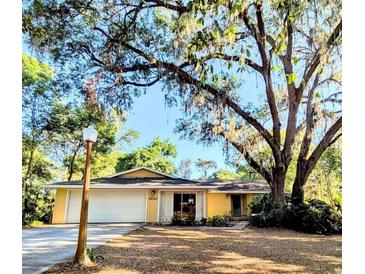 Charming yellow home with mature trees and a well-maintained lawn at 600 Lake St, Fruitland Park, FL 34731