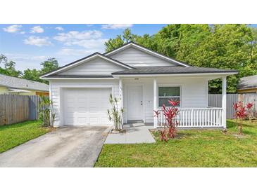 Charming single-story home with an attached garage, front porch, and landscaping at 6148 Landrace Ln, Orlando, FL 32807