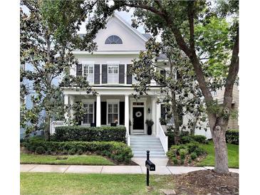 Charming two-story home featuring a welcoming porch, black shutters, and well-manicured landscaping at 616 Nadina Pl, Celebration, FL 34747