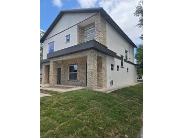 Modern two-story home showcasing stacked stone accents, neutral paint, and a well-manicured lawn at 1005 Randall St, Orlando, FL 32805