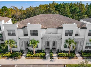 Beautiful townhome exterior with manicured landscaping, stone accents, and palm trees at 17230 Blessing Dr, Clermont, FL 34714