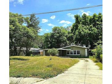 Cozy single-story home with a driveway and a lush green lawn, shaded by mature trees at 1914 Geigel Ave, Orlando, FL 32806