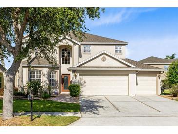 Two-story home with a three car garage, mature trees and landscaping in the front yard at 2704 Gorst Rd, Winter Garden, FL 34787