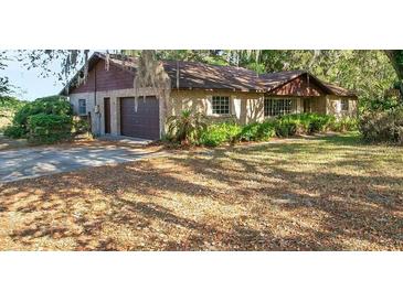 Charming single-story home featuring a brick facade, attached garage, and mature landscaping at 36208 Micro Racetrack Rd, Fruitland Park, FL 34731