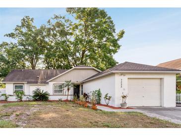Charming one-story home featuring a well-maintained yard and attached garage, complemented by mature trees at 7333 Radiant Cir, Orlando, FL 32810