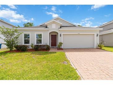 Charming single-story home features a well-manicured lawn, inviting entryway, and attached two-car garage at 928 Avenal Ln, Davenport, FL 33837
