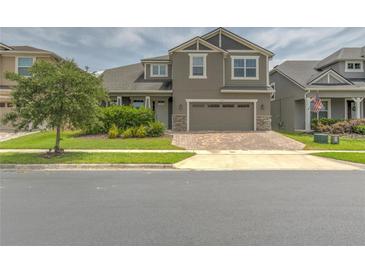 Inviting two-story home featuring a well-manicured lawn and a brick paved driveway leading to a two car garage at 3302 Stonegate Dr, Ocoee, FL 34761
