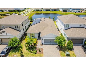 An aerial view of the house with solar panels, landscaping, and a nearby pond at 13864 Destin Beach Ln, Orlando, FL 32827