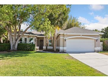Charming single-story home with a well-manicured lawn, mature trees, and an attached two-car garage at 14841 Faversham Cir, Orlando, FL 32826