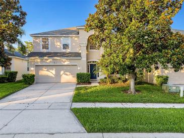 Two story home featuring a manicured front lawn, mature trees, neutral color palette, and attached two car garage at 2609 Dinville St, Kissimmee, FL 34747