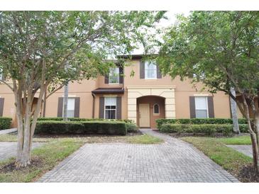 Inviting two-story townhome featuring a brick pathway and mature landscaping, creating curb appeal at 626 Verona Ave, Davenport, FL 33897