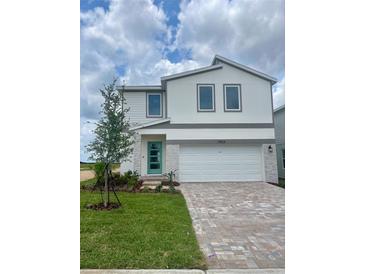 Charming two-story home with a well-maintained lawn, a two-car garage, and a teal front door at 1904 Diamond Head Cir, Lake Hamilton, FL 33851