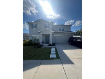 Charming two-story home with blue accents, landscaped lawn, and a two car garage at 5006 Vellacito Way, Davenport, FL 33897