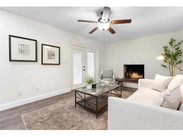 Cozy living room with white brick fireplace, ceiling fan, and French doors leading to the outside at 577 Compton Ct, Deland, FL 32724
