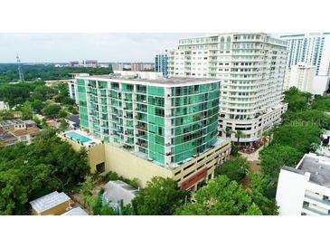 An aerial view of a modern condo building with balconies and pool, surrounded by lush landscaping in an urban area at 101 S Eola Dr # 720, Orlando, FL 32801