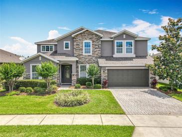 Charming two-story home featuring a stone facade, manicured landscaping, and a paved driveway at 1078 Vinsetta Cir, Winter Garden, FL 34787