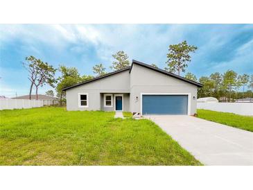 Charming single-story home featuring a blue garage door, well-kept lawn, and a modern roof design at 14957 Sw 63Rd Court Rd, Ocala, FL 34473