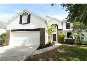Inviting two-story home featuring a two car garage, manicured lawn and a walkway leading to the front door at 1645 Boulder Creek Ct, Apopka, FL 32712