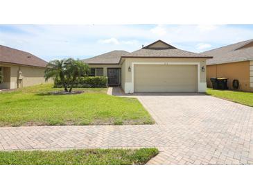 Charming home featuring a paved driveway, two-car garage, well-kept lawn, and a nicely landscaped yard at 212 Regency St, Davenport, FL 33896