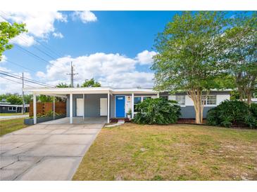 Charming single-story home featuring a bright blue door, covered parking, and mature landscaping at 3520 Sebring Ave, Orlando, FL 32806