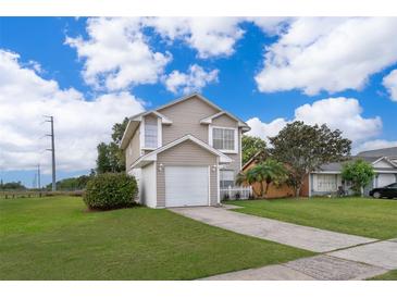 Two-story home with light beige siding, attached garage, and well-maintained lawn under a sunny, partly cloudy sky at 9316 Dubois Blvd, Orlando, FL 32825
