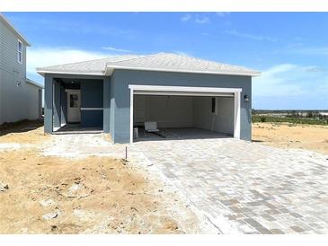 A charming one-story home featuring a gray-blue facade, paved driveway, and attached garage at 1912 Diamond Head Cir, Lake Hamilton, FL 33851