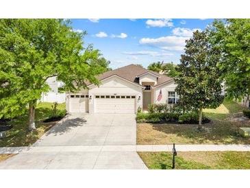 Inviting single-Gathering home featuring a three-car garage, well-manicured lawn, and mature shade trees at 5839 Tarleton Way, Mount Dora, FL 32757